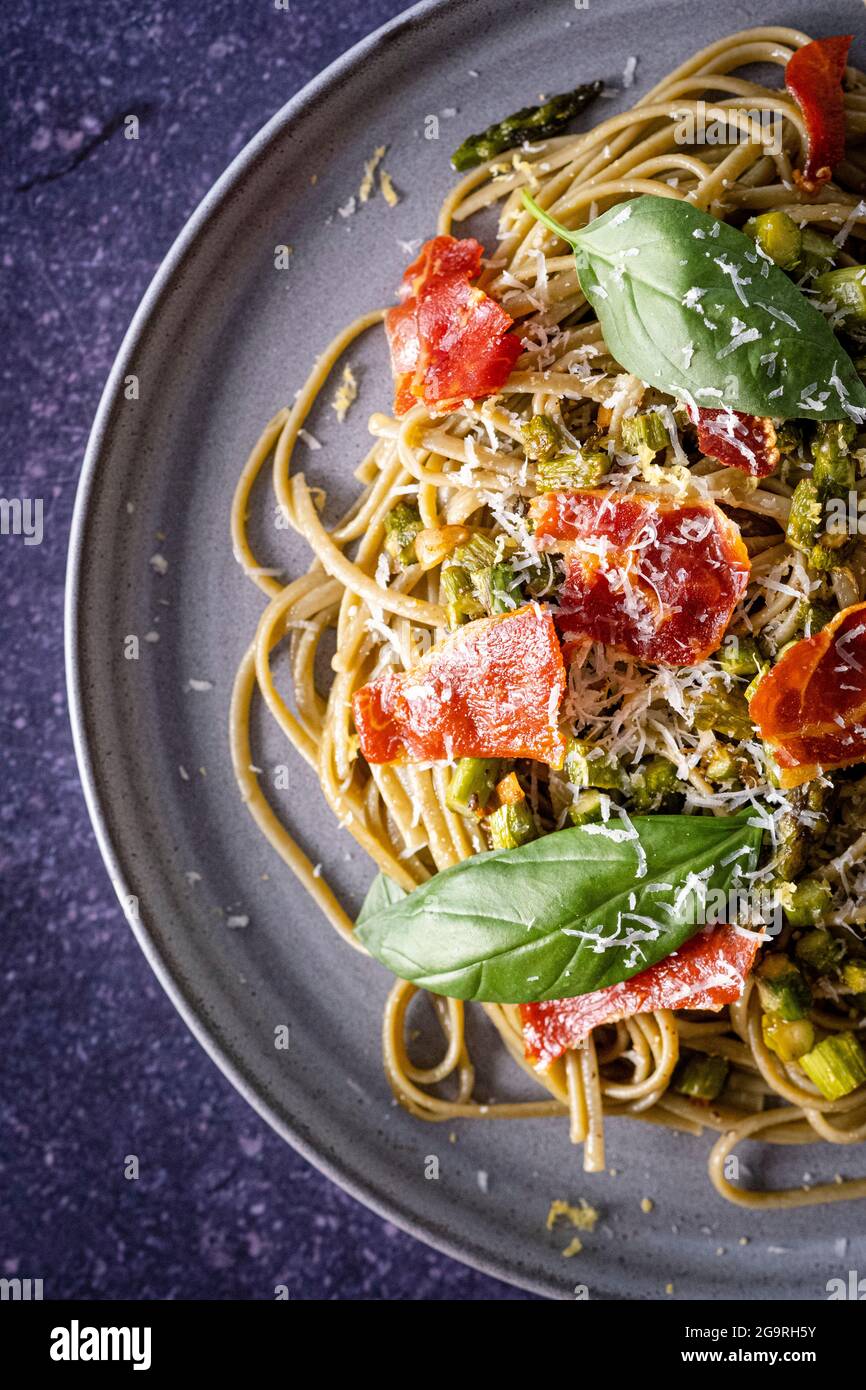 Spaghetti, crispy ham, asparagus,basil and parmesan cheese Stock Photo