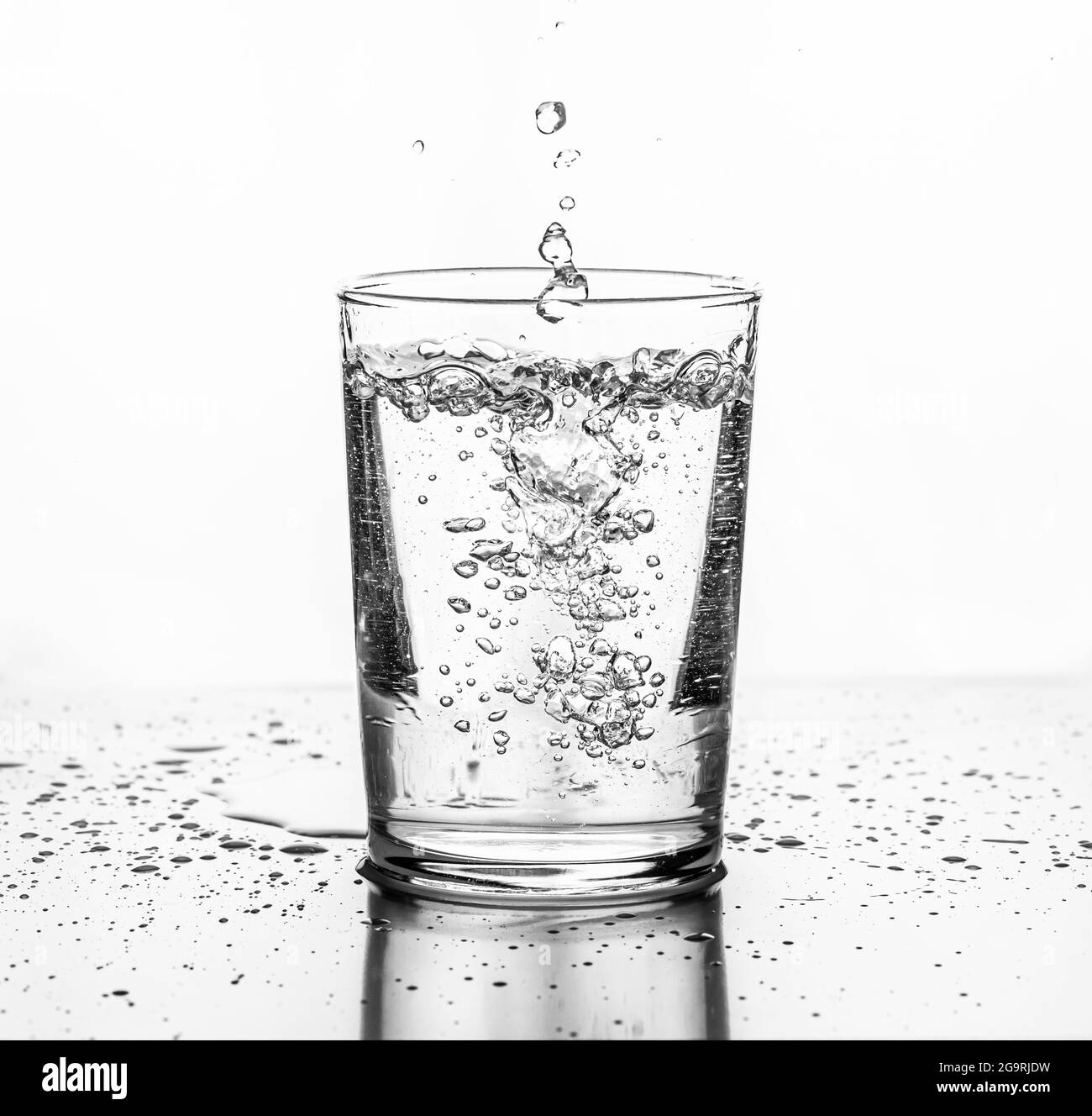 Water being poured into a glass. White background. Stock Photo