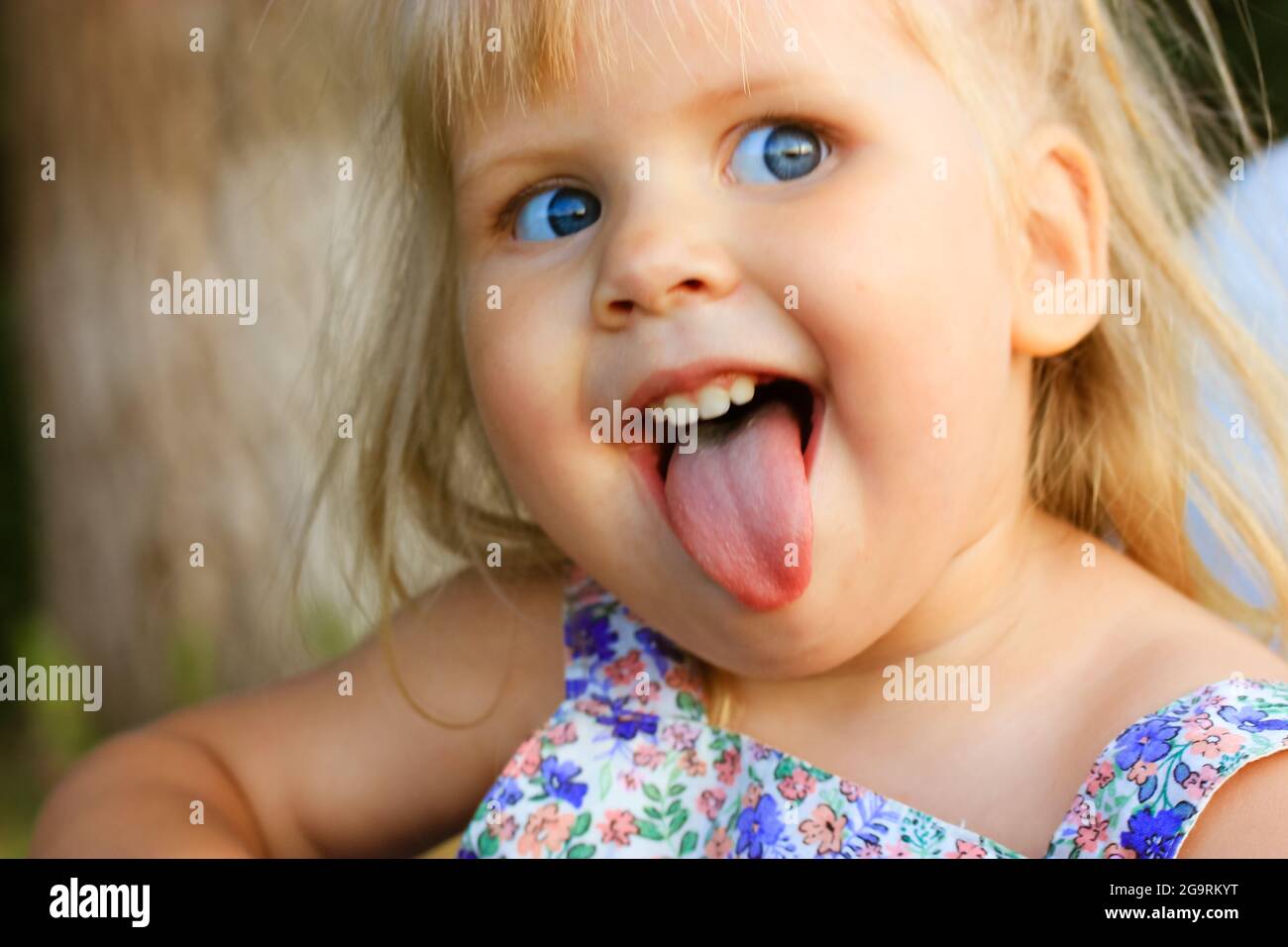 A funny infant baby girl with open mouth and tongue out. Emotional portrait  of a playful cheerful 3 year old happy blonde-haired, blue-eyed beautiful  Stock Photo - Alamy