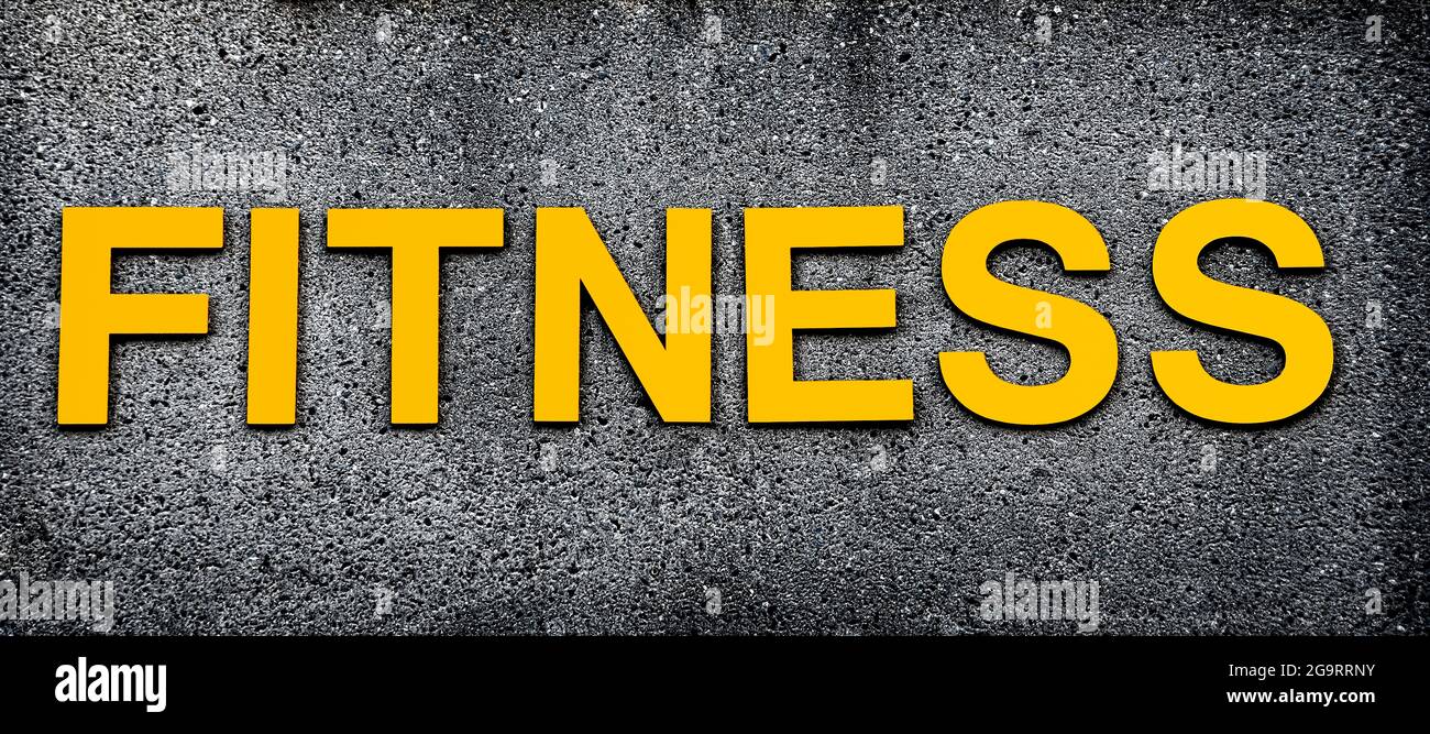 Golden lettering spell out FITNESS against concrete background. Stock Photo