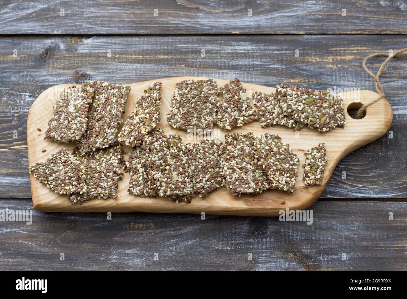 Delicious healthy multigrain gluten-free crackers, ketogenic, from chia seeds, flax, sesame and ground pumpkin seeds on a wooden board and on a wooden Stock Photo