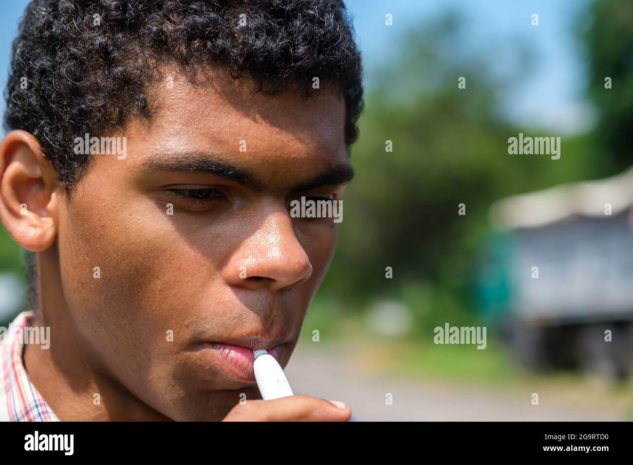 African American man smoking electronic cigarette with e-liquid outdoors Stock Photo