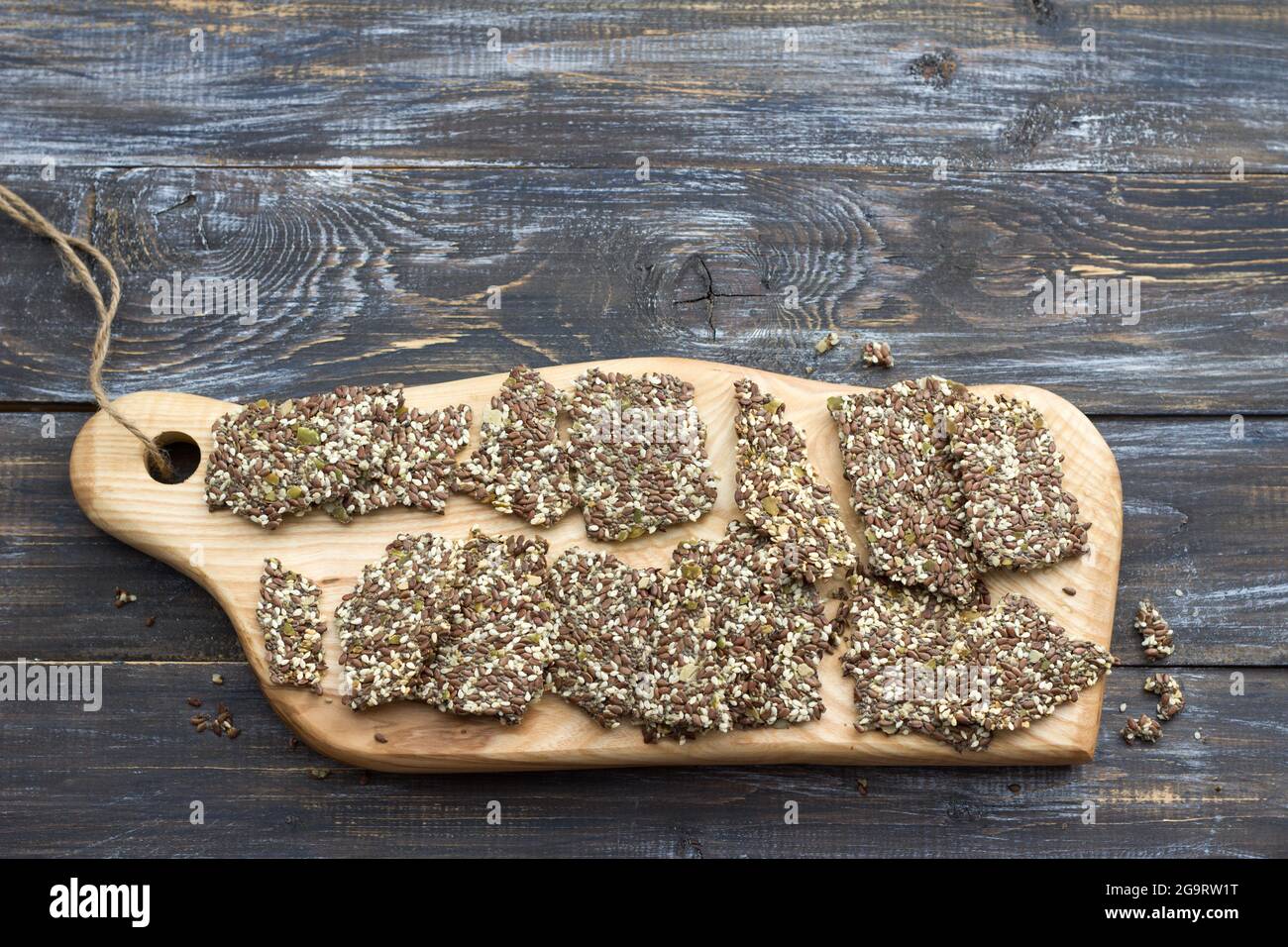 Delicious healthy multigrain gluten-free crackers, ketogenic, from chia seeds, flax, sesame and ground pumpkin seeds on a wooden board and on a wooden Stock Photo