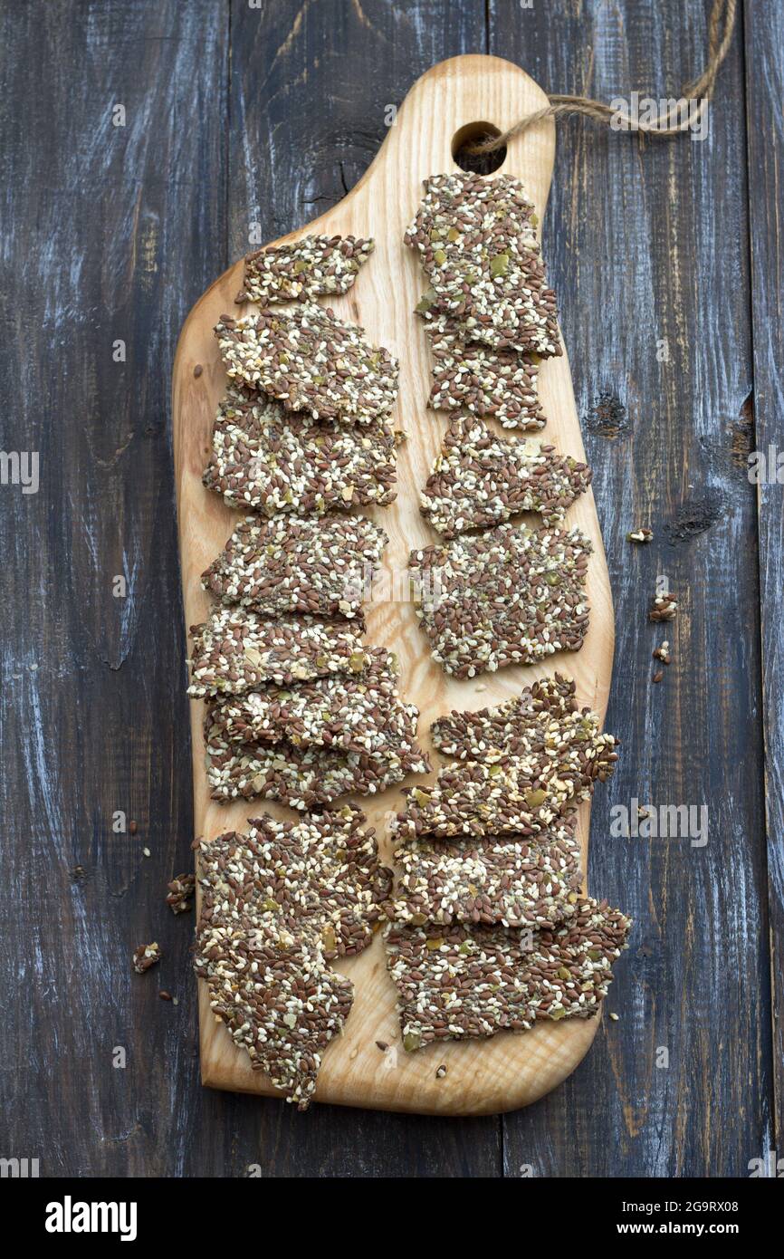 Delicious healthy multigrain gluten-free crackers, ketogenic, from chia seeds, flax, sesame and ground pumpkin seeds on a wooden board and on a wooden Stock Photo