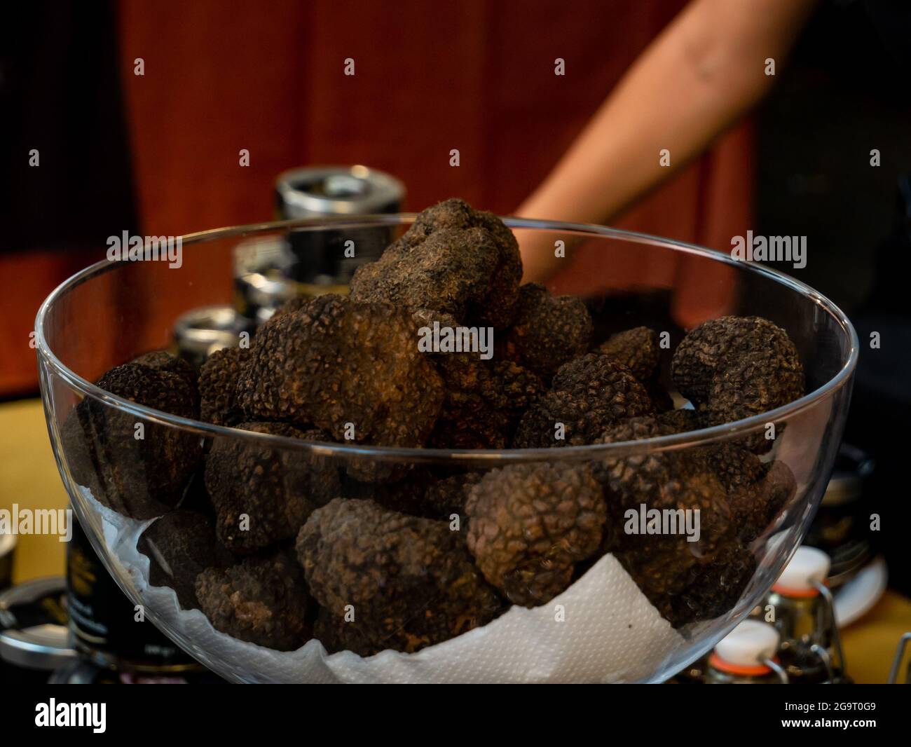 a glass bowl with many truffle mushrooms inside on display at a market counter Stock Photo