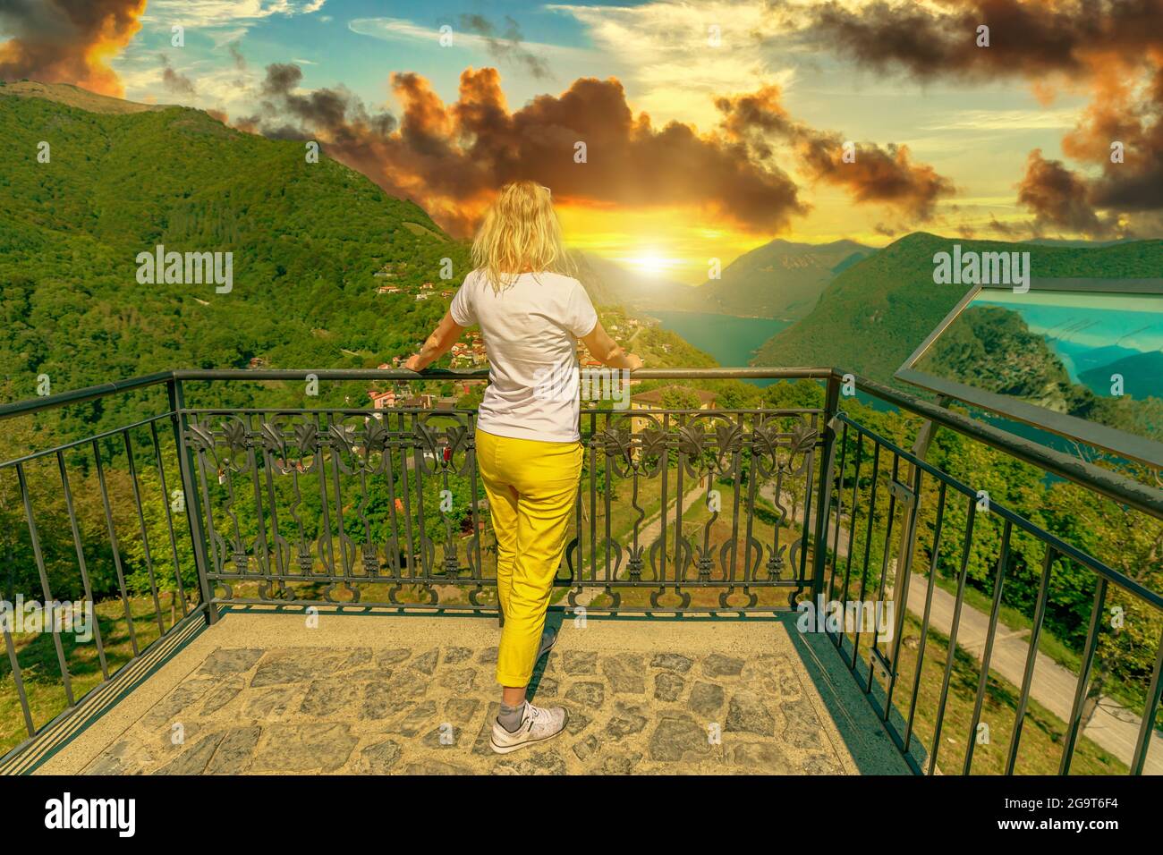 elegant woman at sunset on top of Lugano Swiss city by Lugano Lake in Switzerland. Aerial view lookout from Monte Bre Mount. Lugano cityscape with Bre Stock Photo