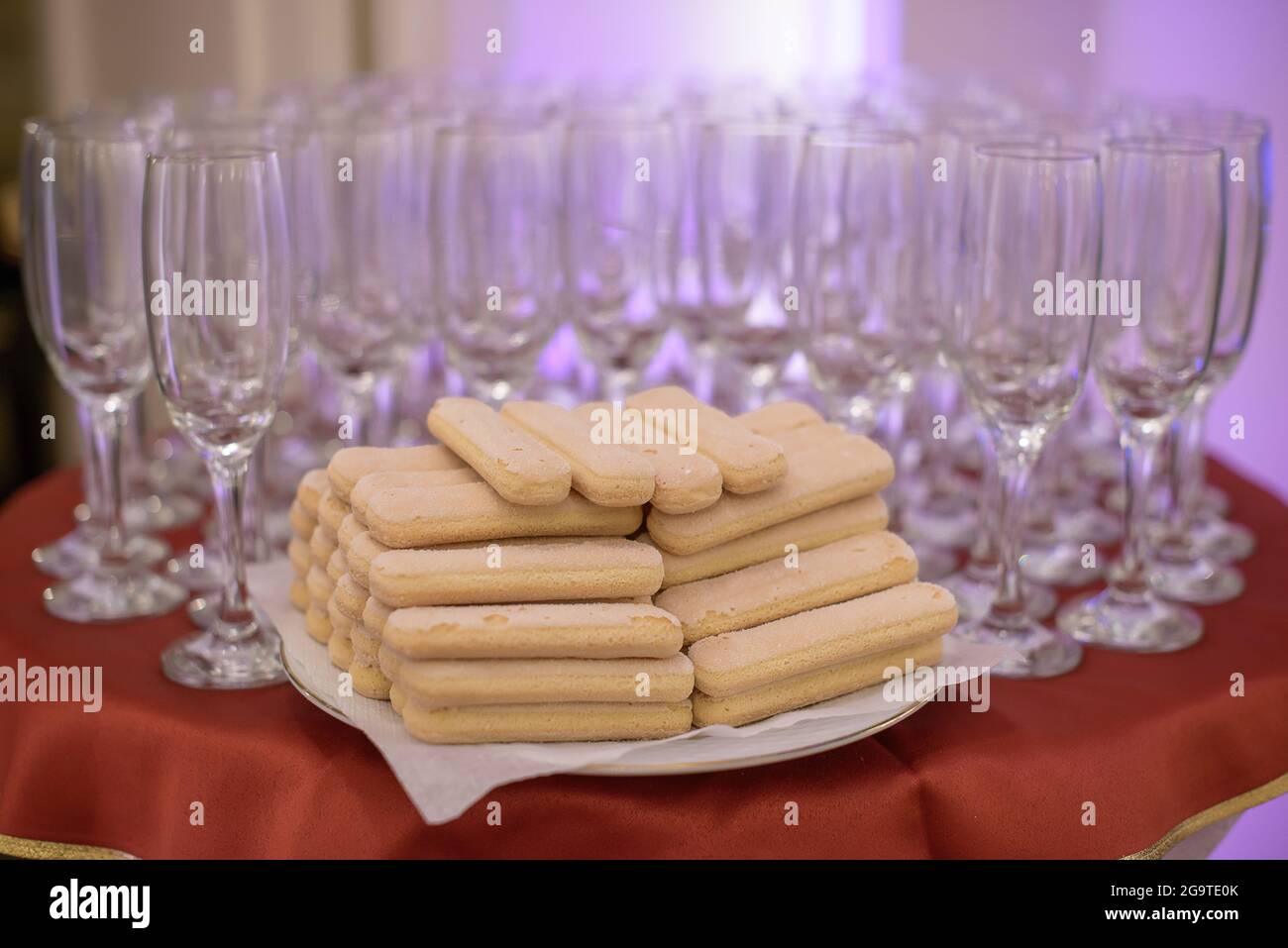 Event or wedding reception table arrangement featuring empty flutes for champagne or bubbly drinks and ladyfinger sponge biscuits, prepared for guests Stock Photo