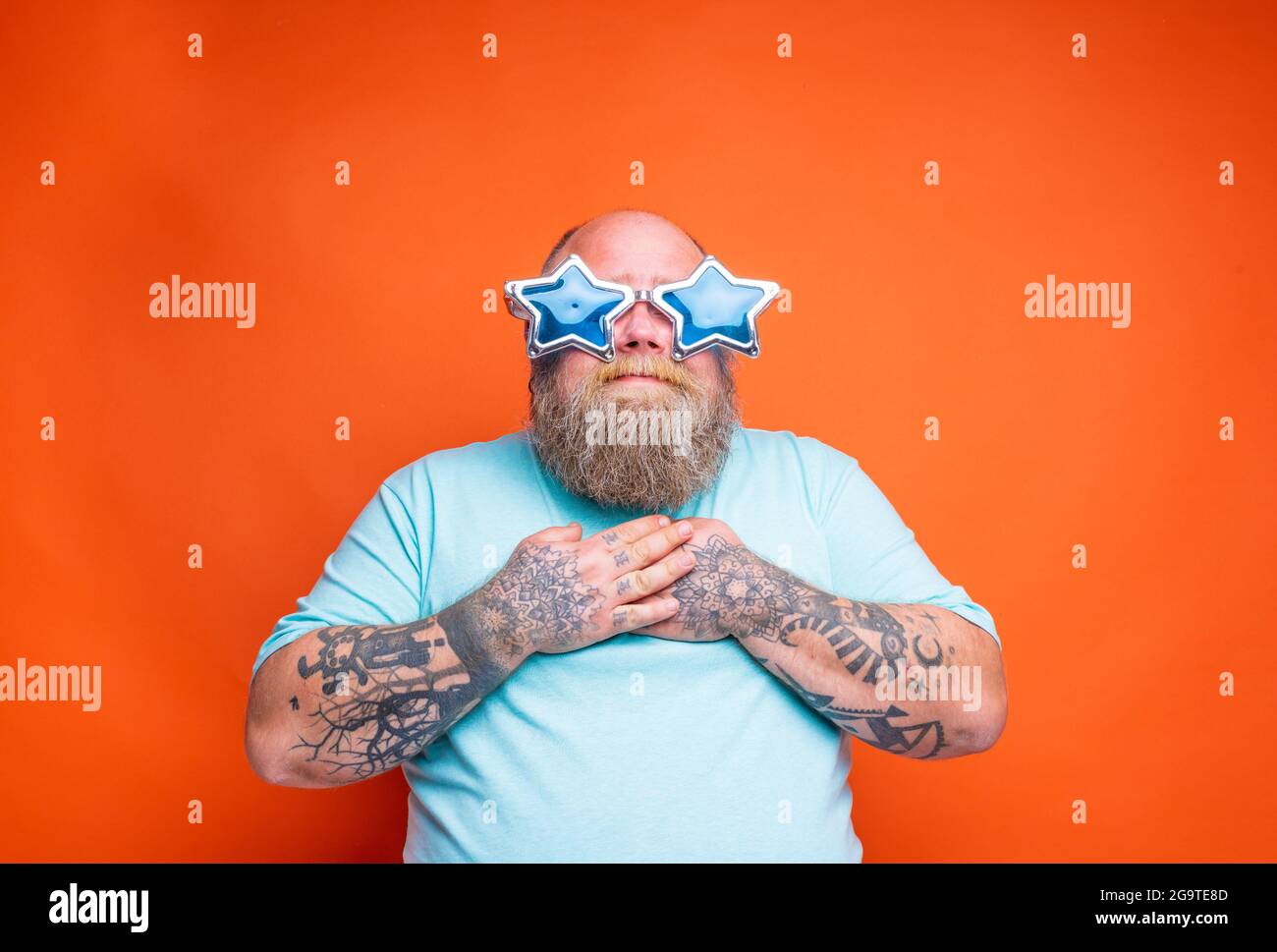 Fat amazed man with beard, tattoos and sunglasses is surprised for something Stock Photo