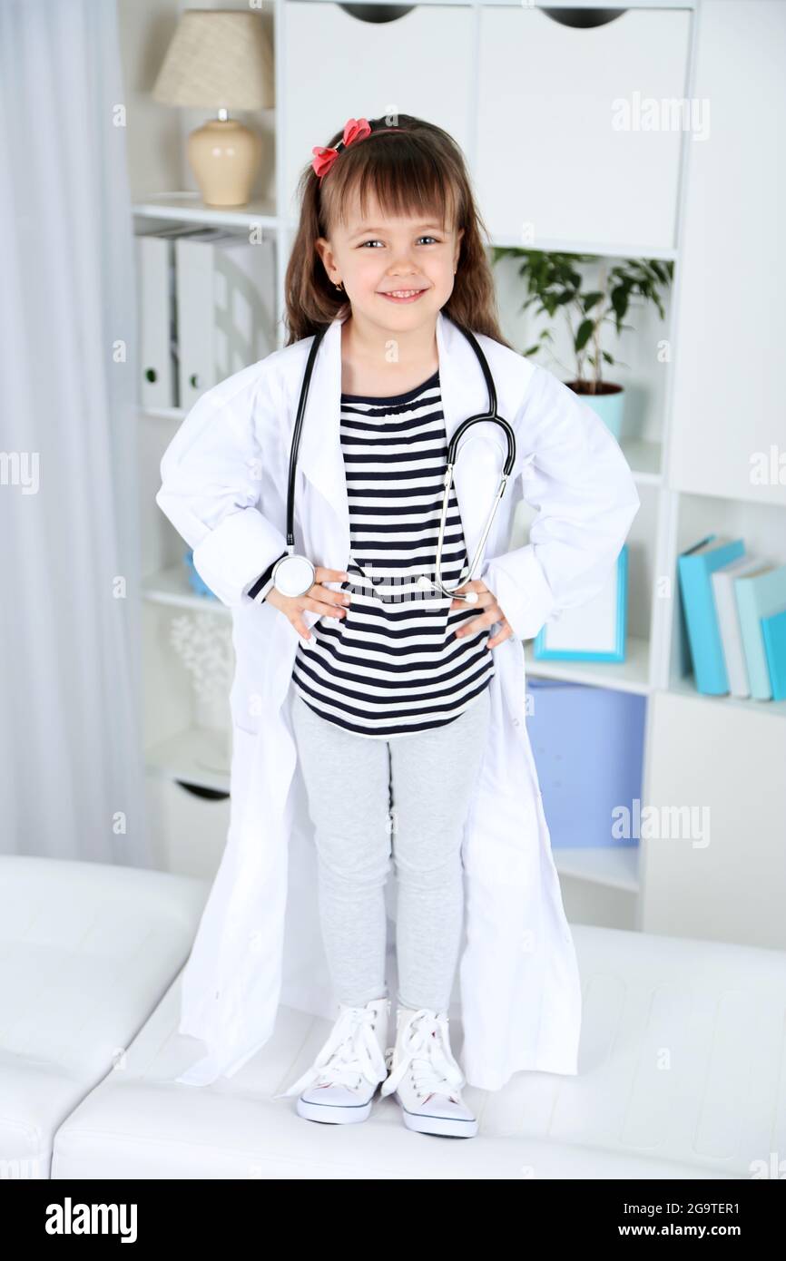 Little girl in doctor costume with stethoscope on office interior