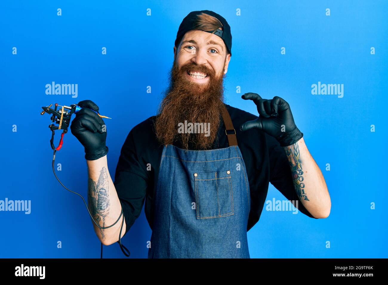 Redhead man with long beard tattoo artist wearing professional uniform and  gloves smiling and confident gesturing with hand doing small size sign with  Stock Photo - Alamy