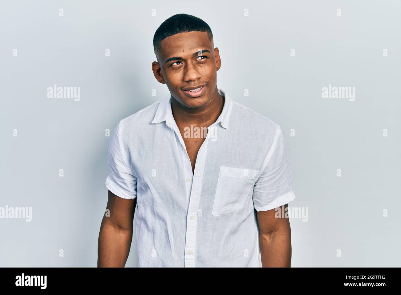 Young black man wearing casual white shirt looking away to side with ...