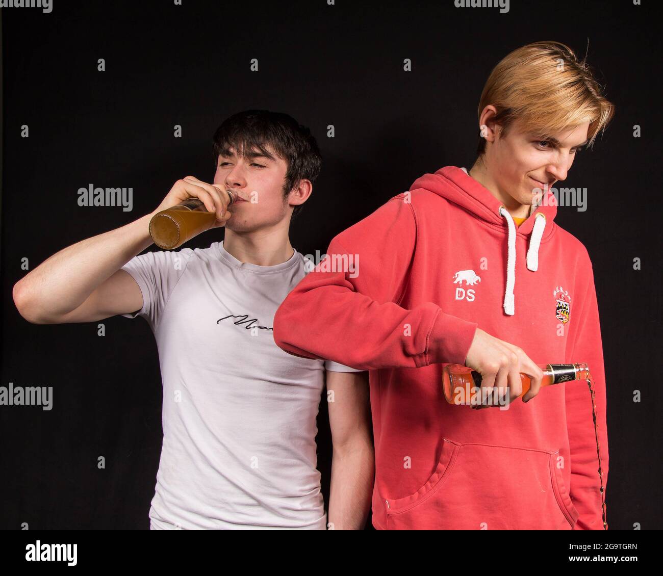 A male youth pours away his beer, feeling peer pressure to take a drink of alcohol Stock Photo
