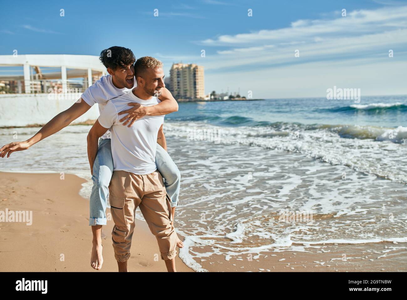Lovely gay couple on piggyback ride at the beach Stock Photo - Alamy
