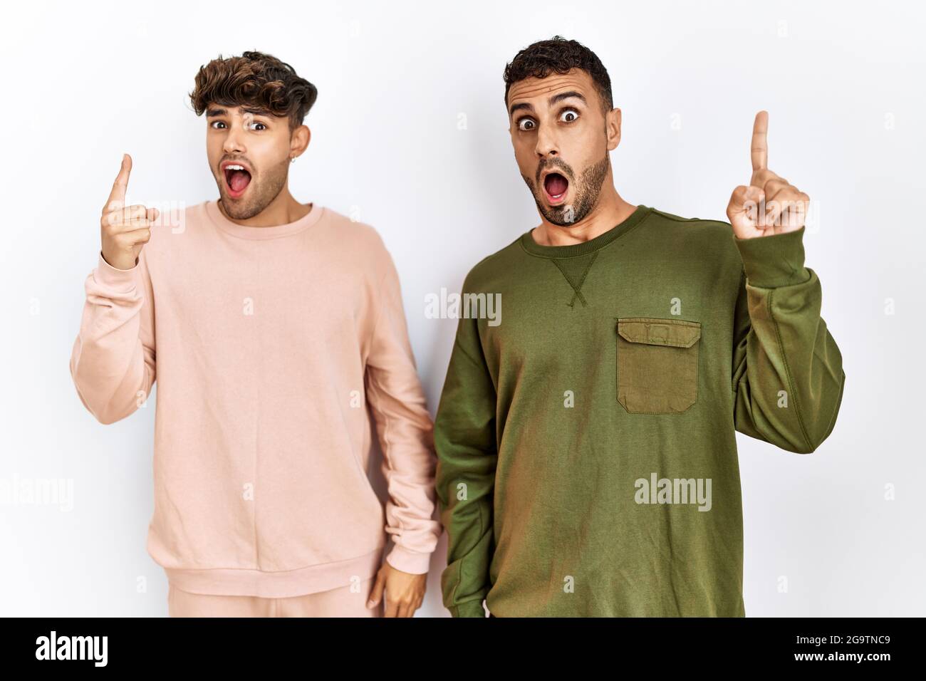 Young gay couple standing over isolated white background pointing finger up  with successful idea. exited and happy. number one Stock Photo - Alamy