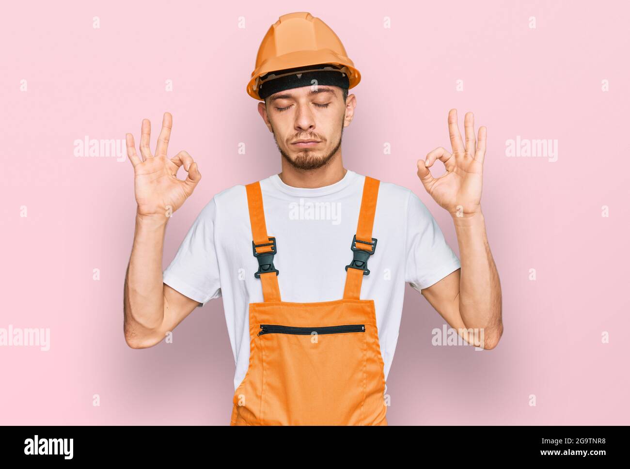 Hispanic young man wearing handyman uniform and safety hardhat relax ...