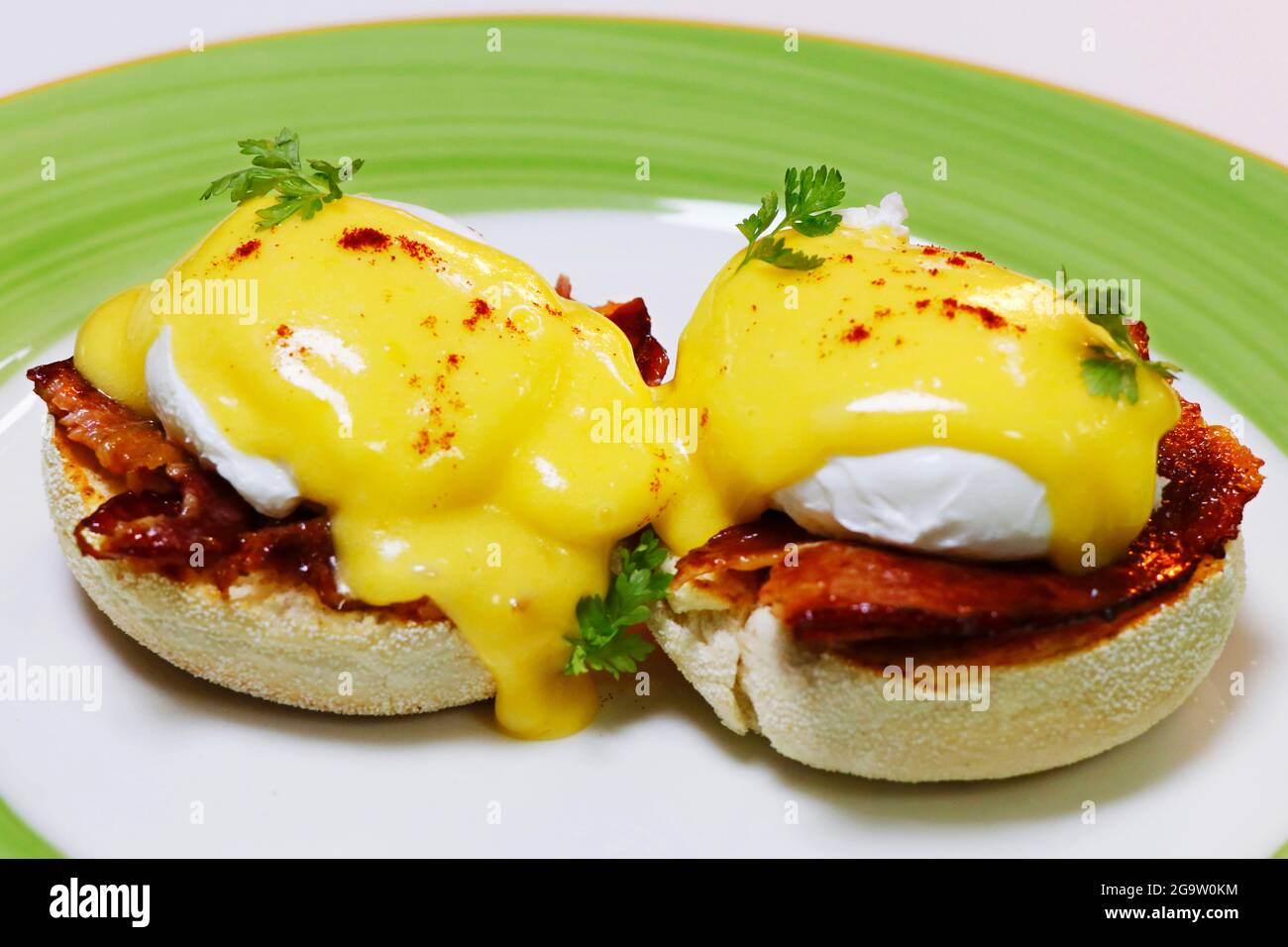 egg benedict on english muffin with pork or beef bacon with rich creamy hollandaise sauce Stock