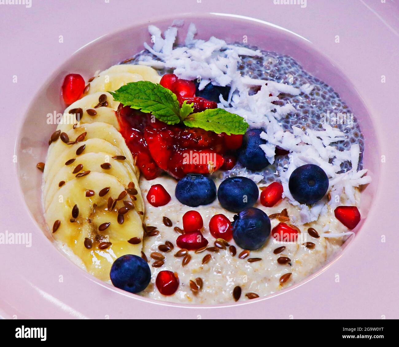 overnight soaked oatmeal and chia bowl with banana, coconut and fresh assorted berries. healthy breakfast concept Stock Photo