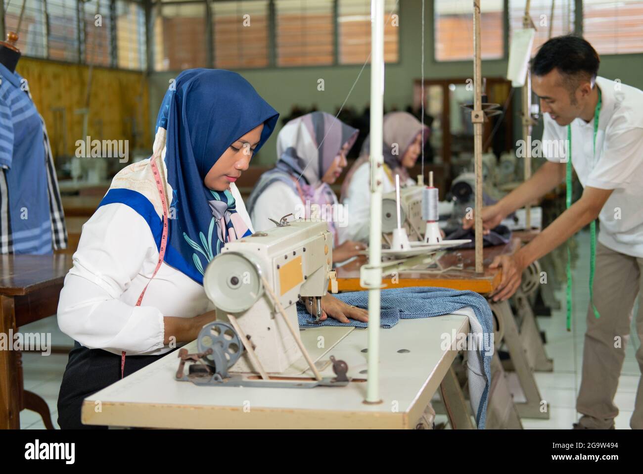 veiled female employees work using sewing machines Stock Photo