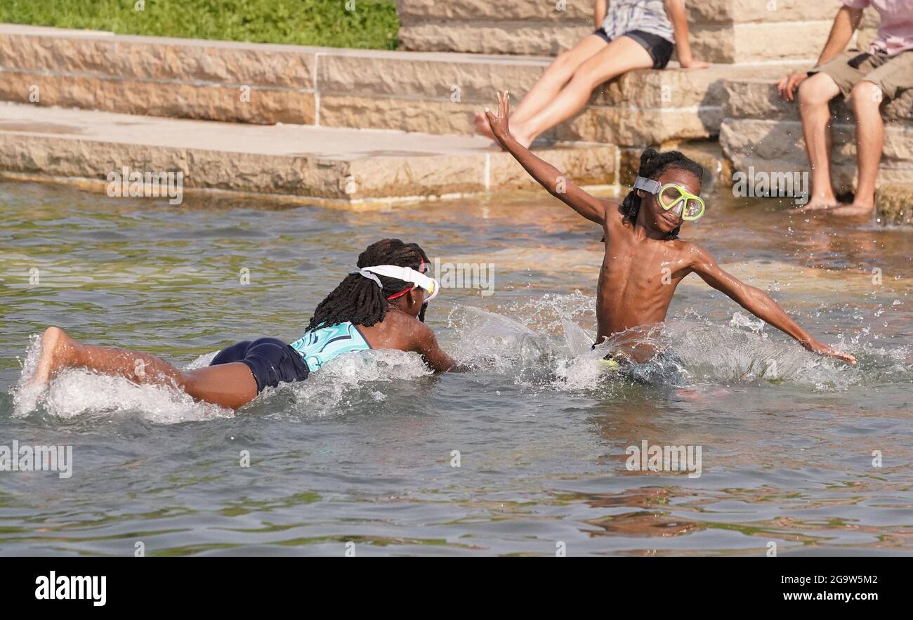 St. Louis, United States. 27th July, 2021. Cortez Henry (7) (R) and Shantie Bailey (10) play in the cool waters of the fountain near the Worlds Fair Pavilion in Forest Park in St. Louis on Tuesday, July 27, 2021. Temperatures reached 94 degrees on the day. Photo by Bill Greenblatt/UPI Credit: UPI/Alamy Live News Stock Photo