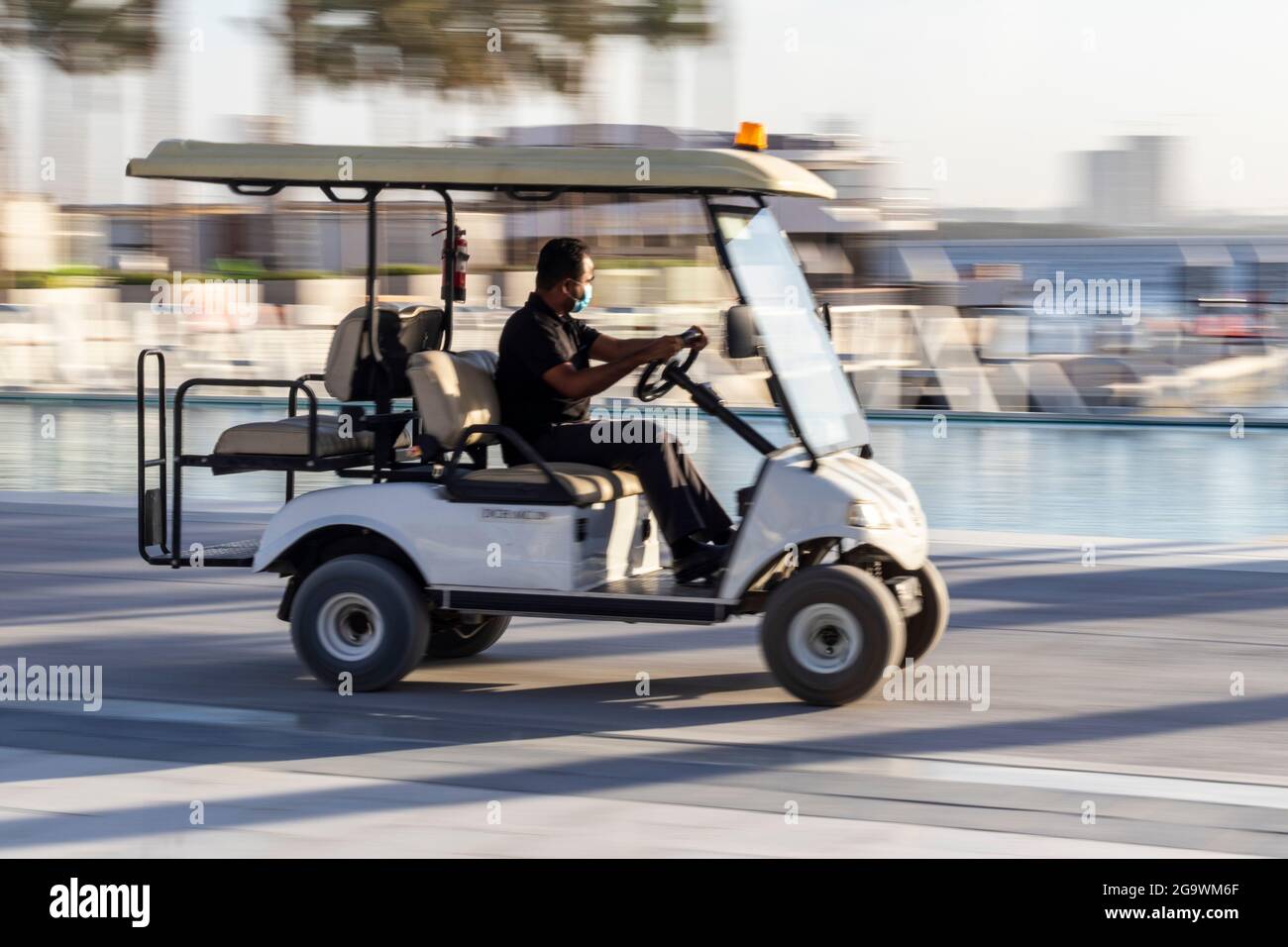 Panning shot of a man driving golf car Stock Photo