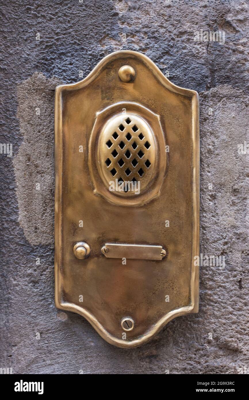 Old fashioned brass door bell intercom on wall in Lucca in Italy Stock Photo