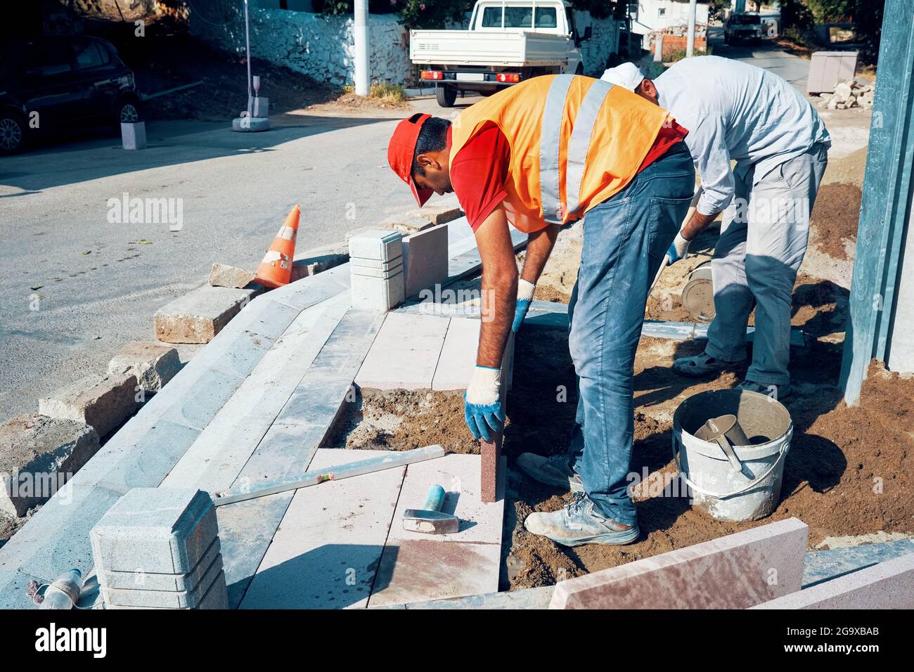 Pavement construction workers installing tiles to build a sidewalk. Stock Photo