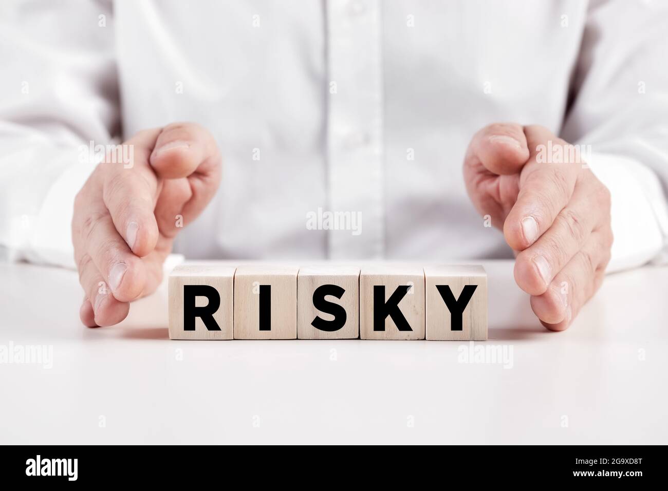 Businessman hands covers the wooden cubes with the word risky Stock Photo