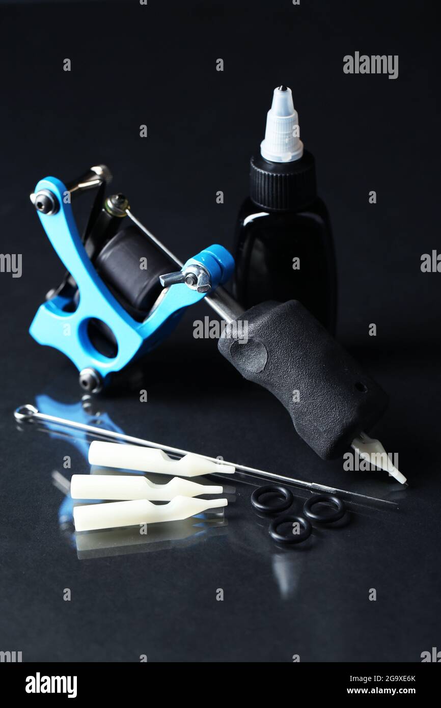 Tattoo machine and tattoo Supplies, on dark background Stock Photo - Alamy