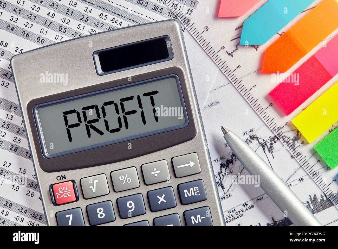 Office desktop with calculator displaying the word profit. Profit calculation, profitability, business, finance or accounting concept. Stock Photo