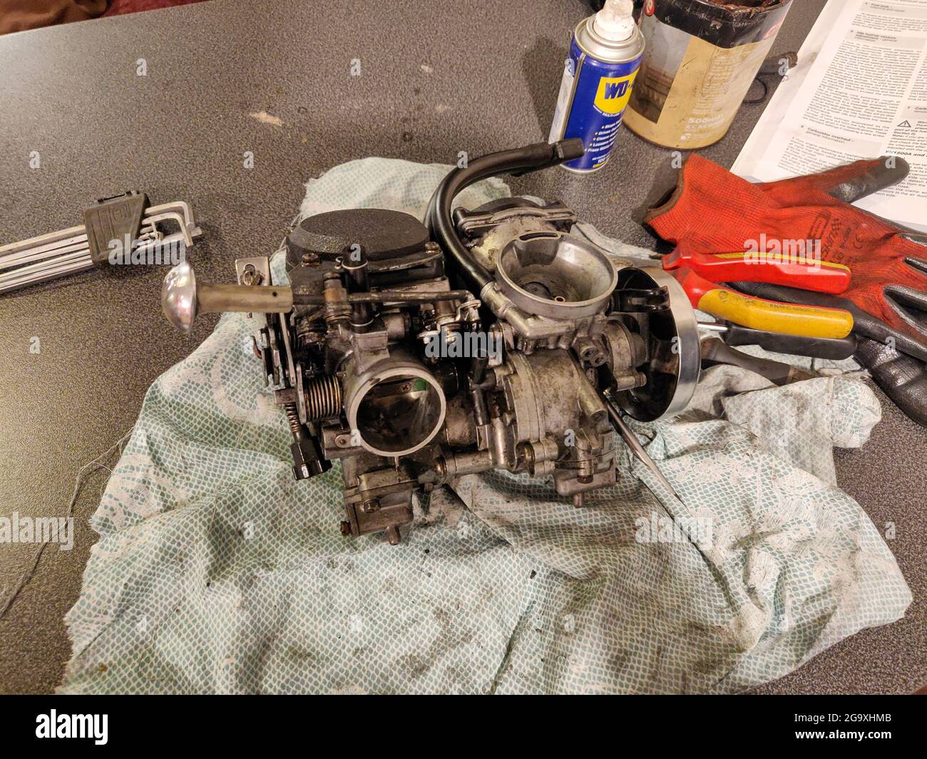 BOURNEMOUTH, UNITED KINGDOM - Jul 08, 2021: A V-Twin Carburettor on a bBench with WD-40 and tools in a repair shop in Bournemouth, United Kingdom Stock Photo