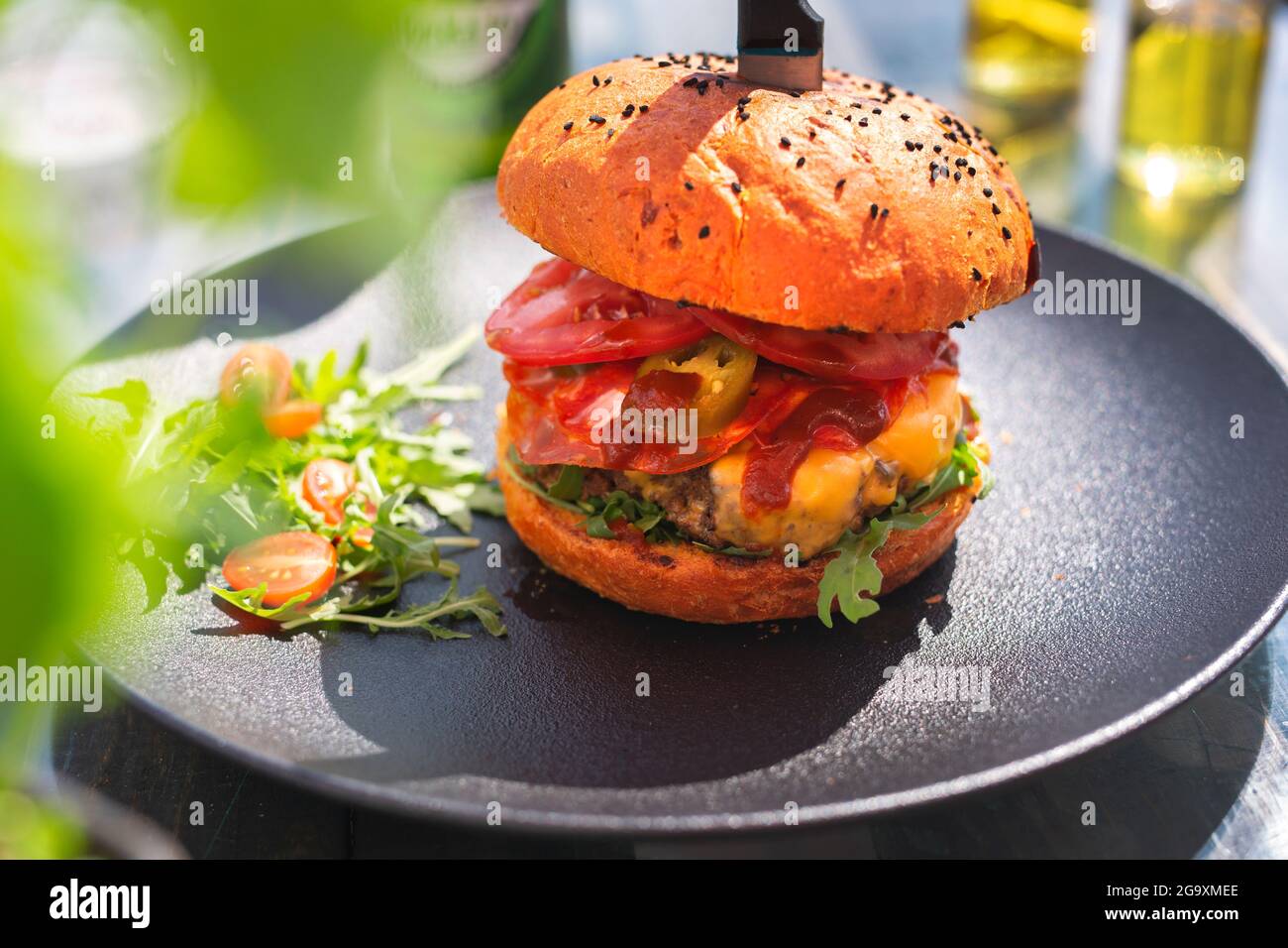 Burger with beef and vegetables, vegetable salad. Fast food. The cook cooks and serves an appetizing dish. The finished dish served on a plate. Servin Stock Photo