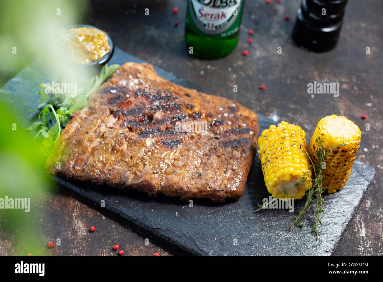 Grilled barbecue ribs, grilled corn cob, mustard sauce. The cook cooks and serves an appetizing dish. The finished dish served on a plate. Serving pro Stock Photo