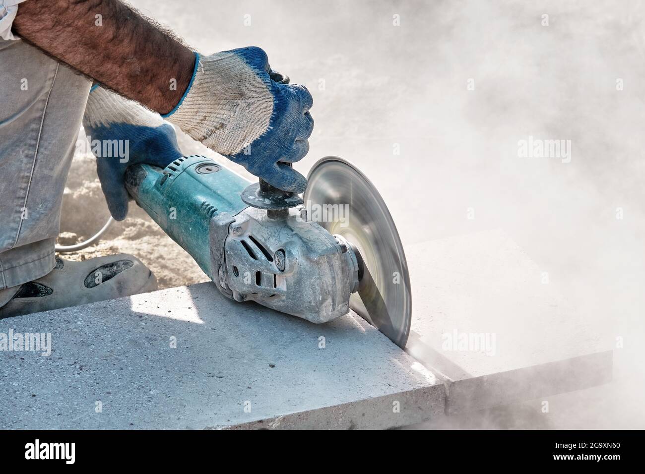 Hands of a pavement construction worker using an angle grinder for