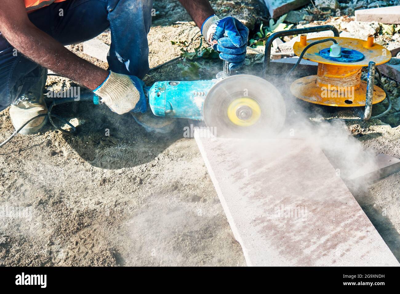 Hands of a pavement construction worker using an angle grinder for