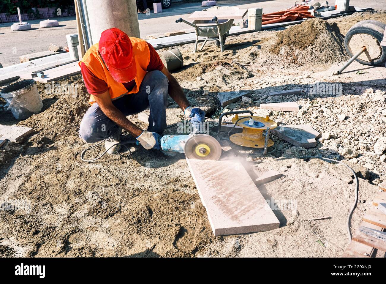 Pavement construction worker using an angle grinder for cutting the