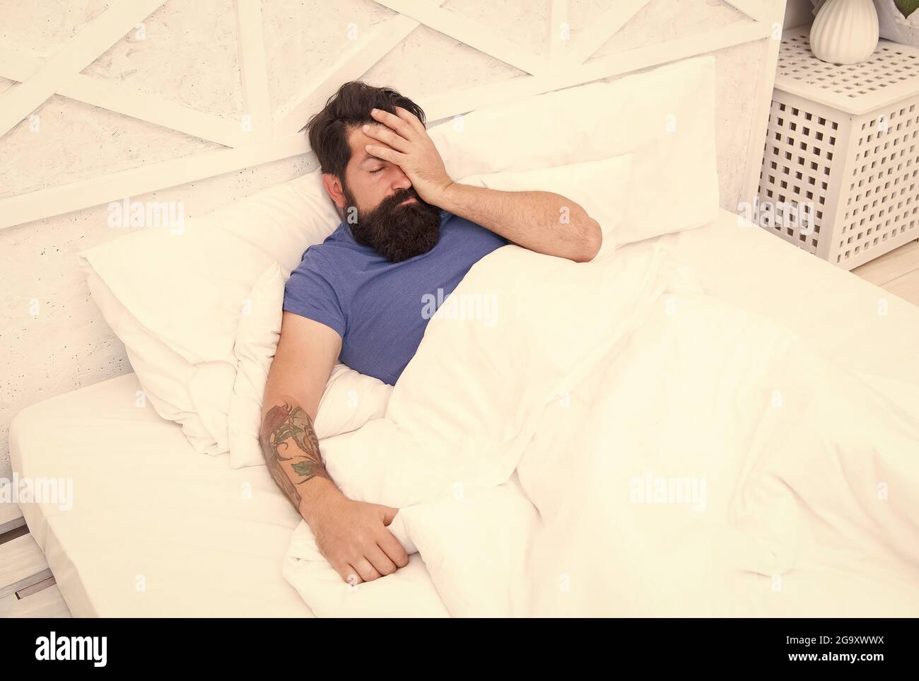 oh no. bachelor has hangover. guy at bedroom. lazy sunday. bed time routine. brutal male wake up with headache. relax lifestyle concept. tired bearded Stock Photo