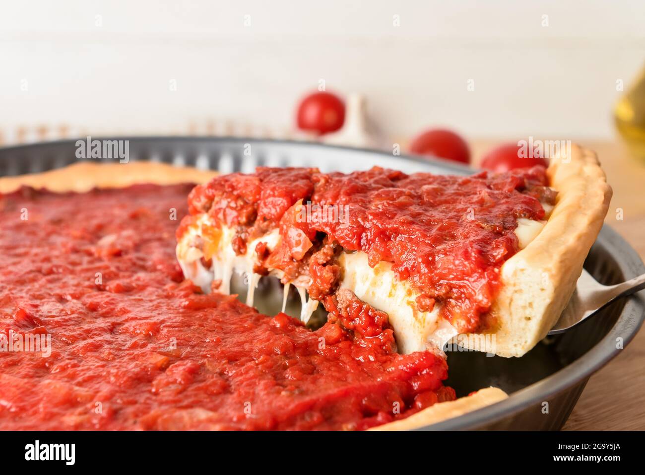Baking dish with tasty Chicago-style pizza on light background, closeup Stock Photo