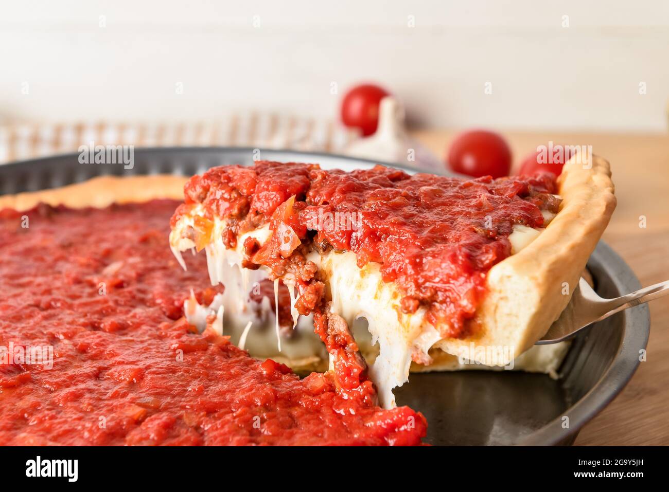 Baking dish with tasty Chicago-style pizza on light background, closeup Stock Photo