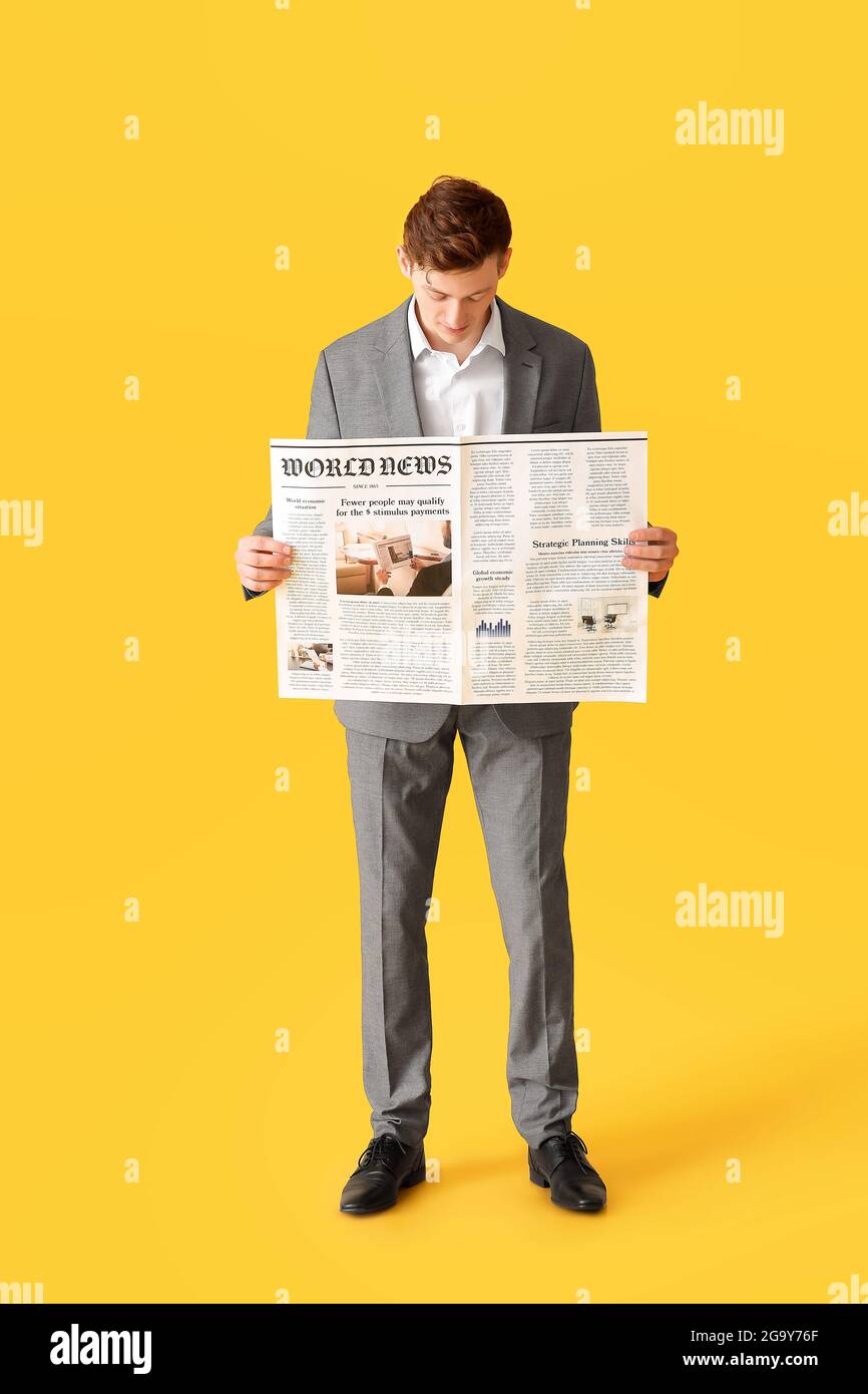 Young businessman reading newspaper on color background Stock Photo