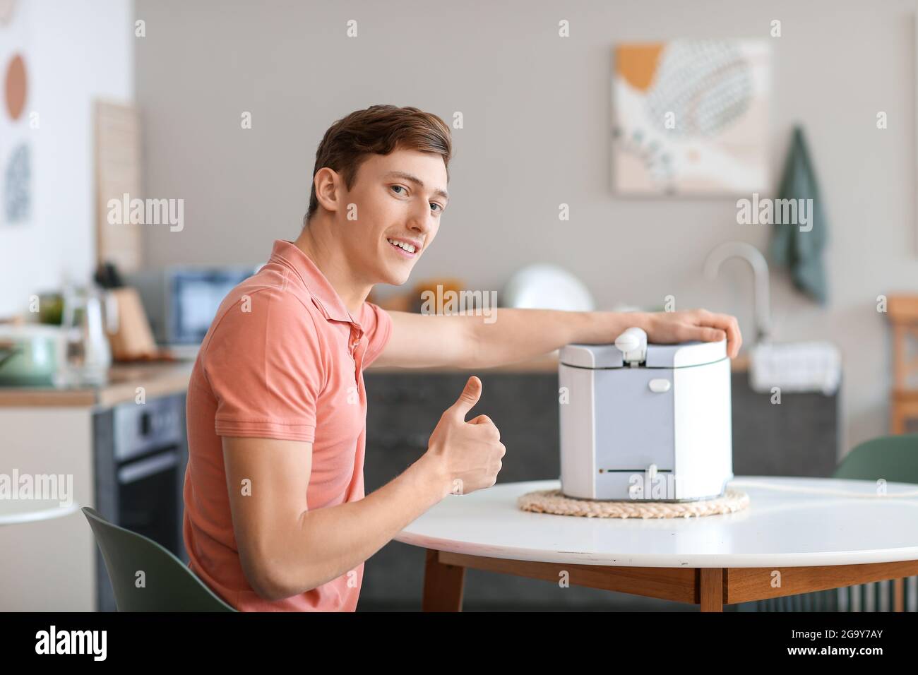 Young man with modern deep fryer showing thumb-up in kitchen Stock ...