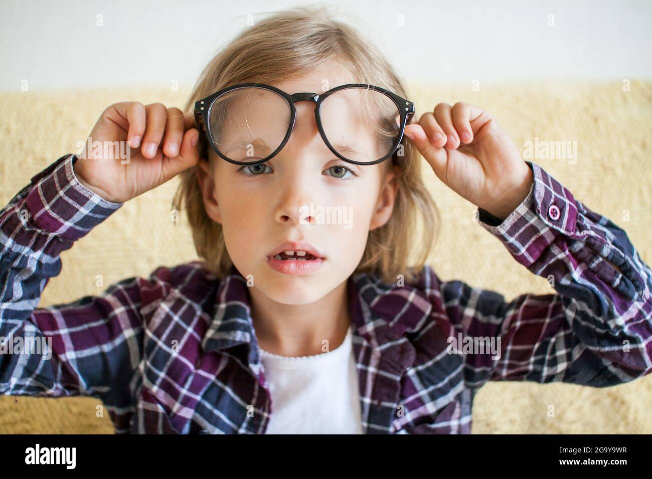 Tired, sleepy girl in a plaid shirt and glasses. Online learning concept. Stock Photo
