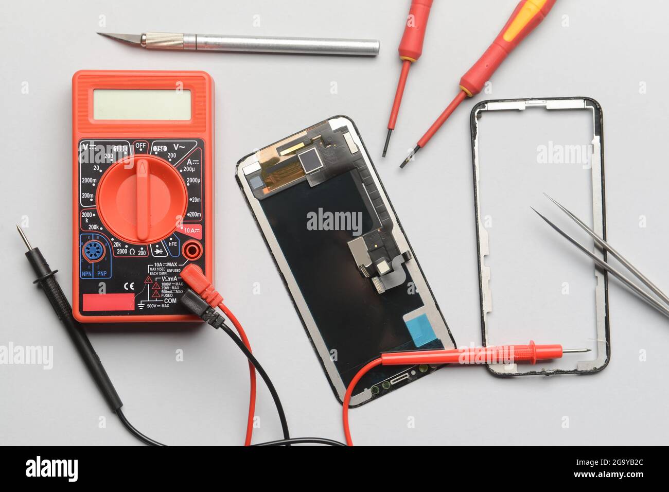 Disassembled mobile phone with technician tools on grey background Stock Photo