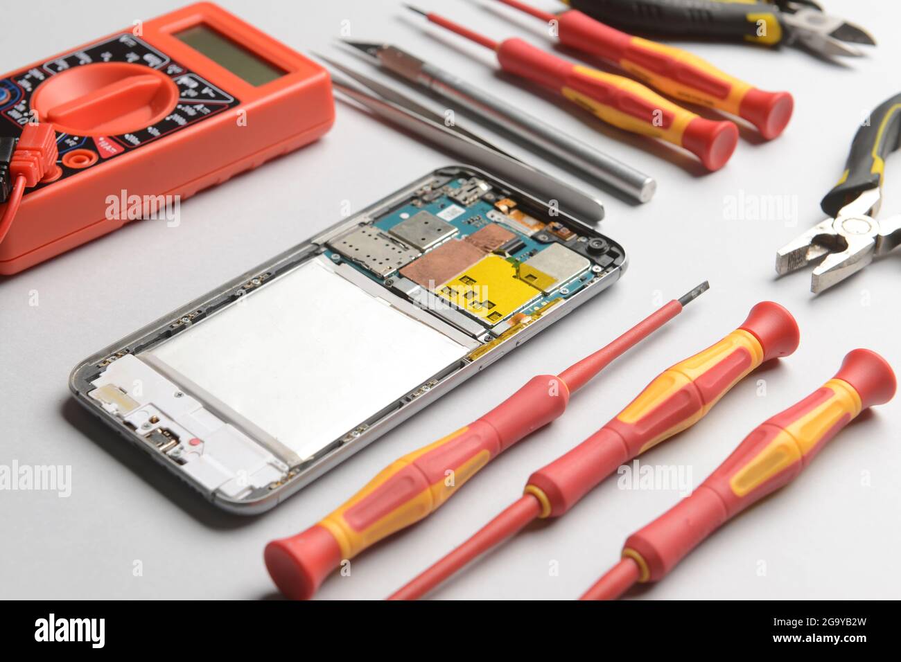 Disassembled mobile phone with technician tools on grey background Stock Photo