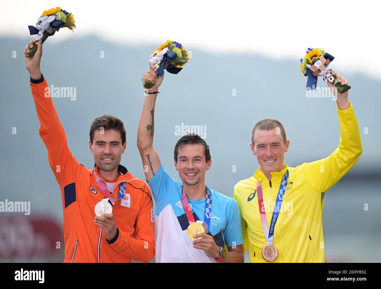 Oyama, Japan. 28th July, 2021. Cycling: Olympics, Oyama (44.20km), men's individual time trial at Fuji International Speedway. Primoz Roglic (M) of Slovenia celebrates his gold medal with silver medallist Tom Dumoulin (l) of the Netherlands and bronze medallist Rohan Dennis of Australia at the award ceremony. Credit: Sebastian Gollnow/dpa/Alamy Live News Stock Photo