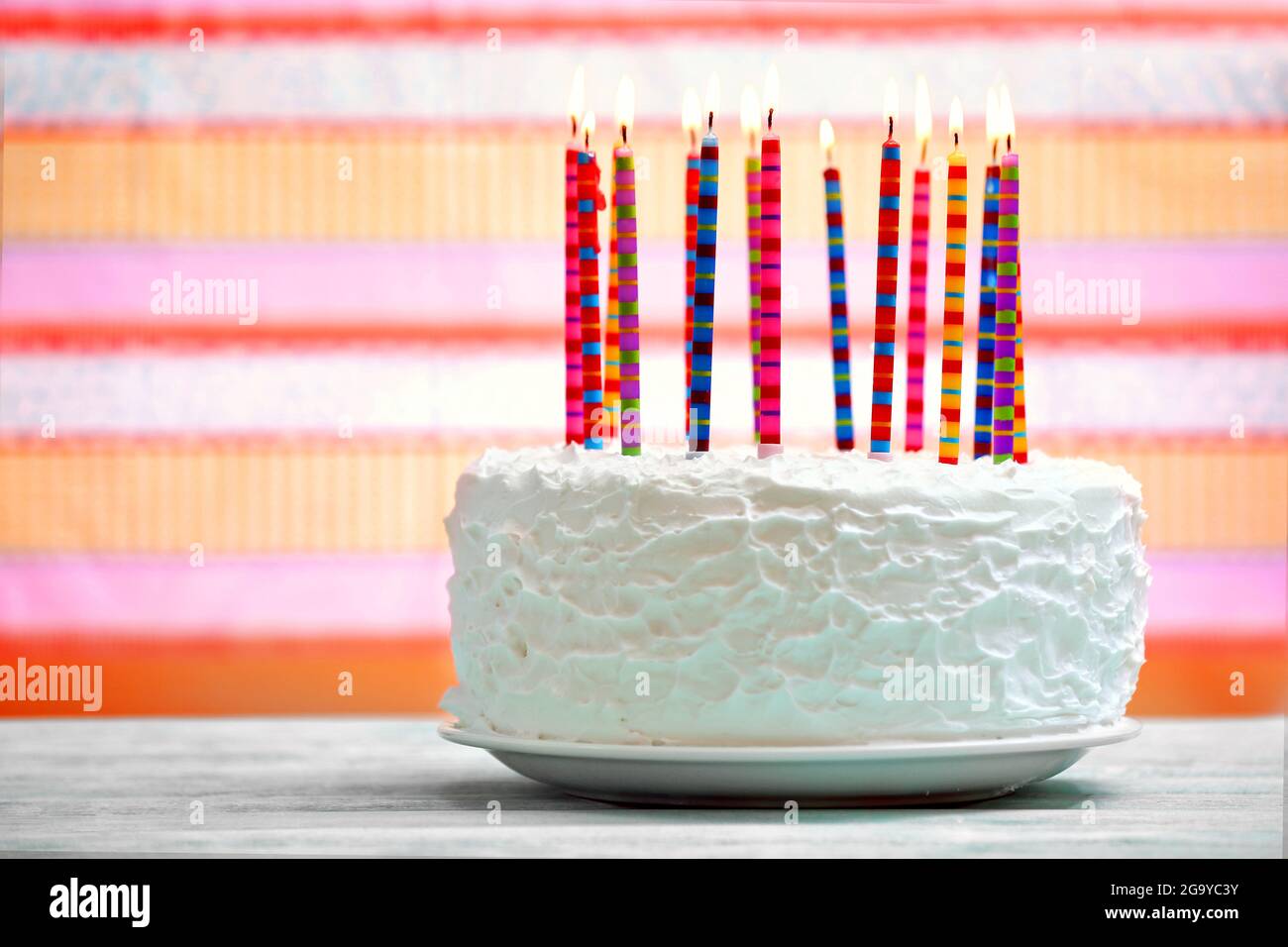 Birthday cake with candles on colorful striped background Stock Photo ...