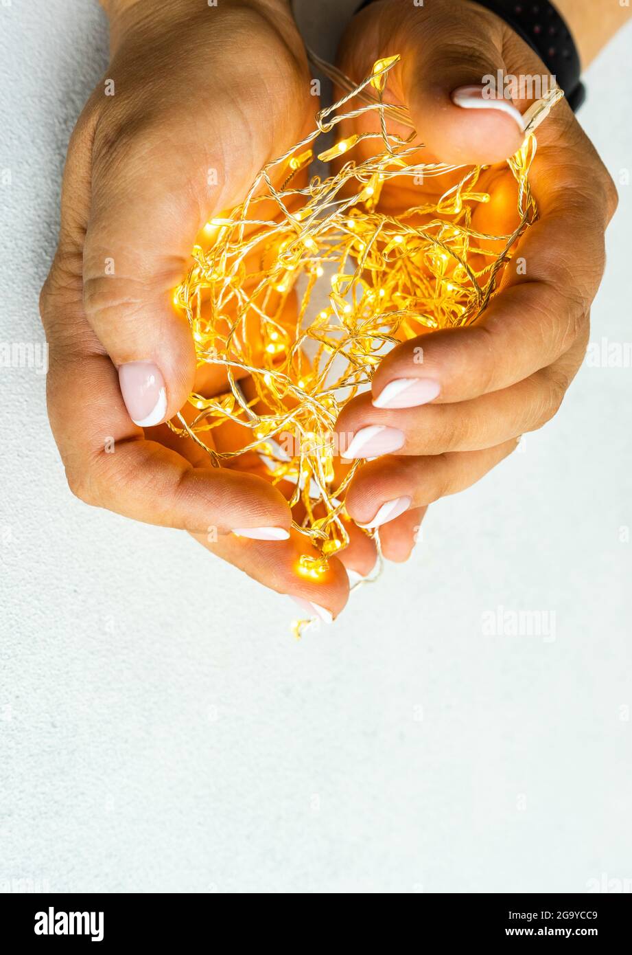 Close-up of woman's hands holding illuminated string lights Stock Photo