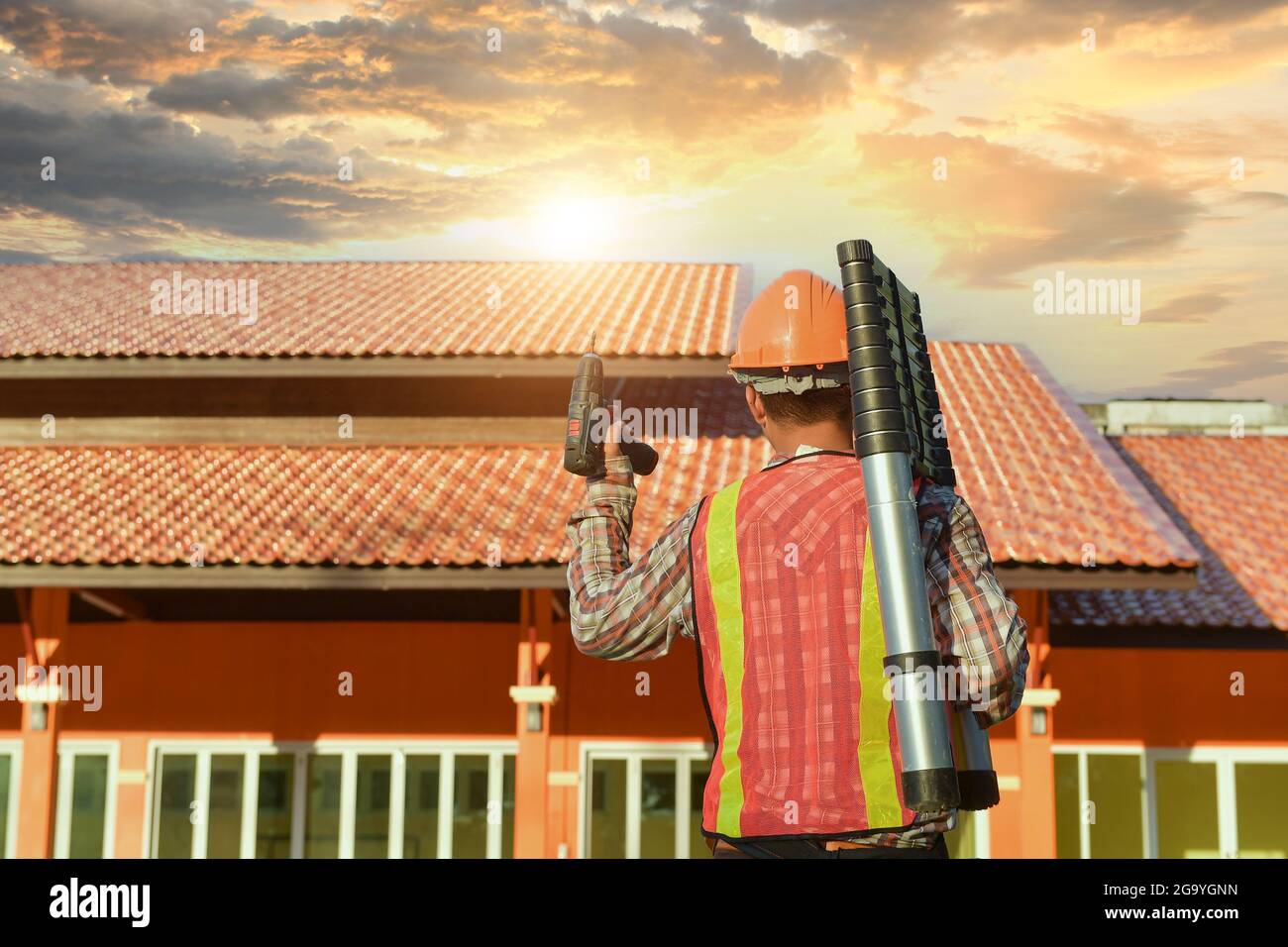 Rear view of a construction worker with tools standing in front of a building, Thailand Stock Photo