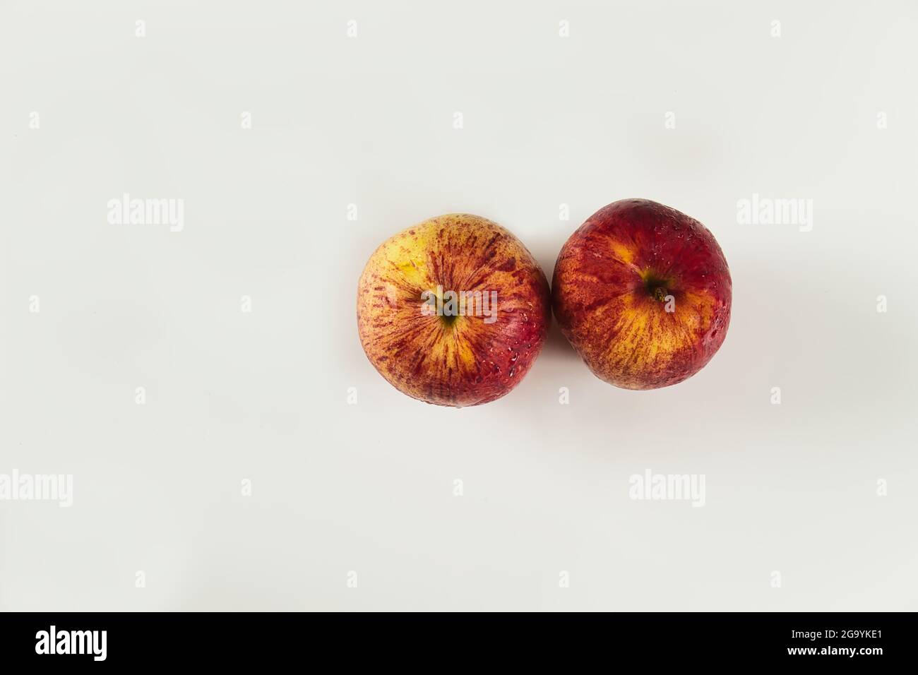 foreground of two red apples with drops on white background viewed from above Stock Photo