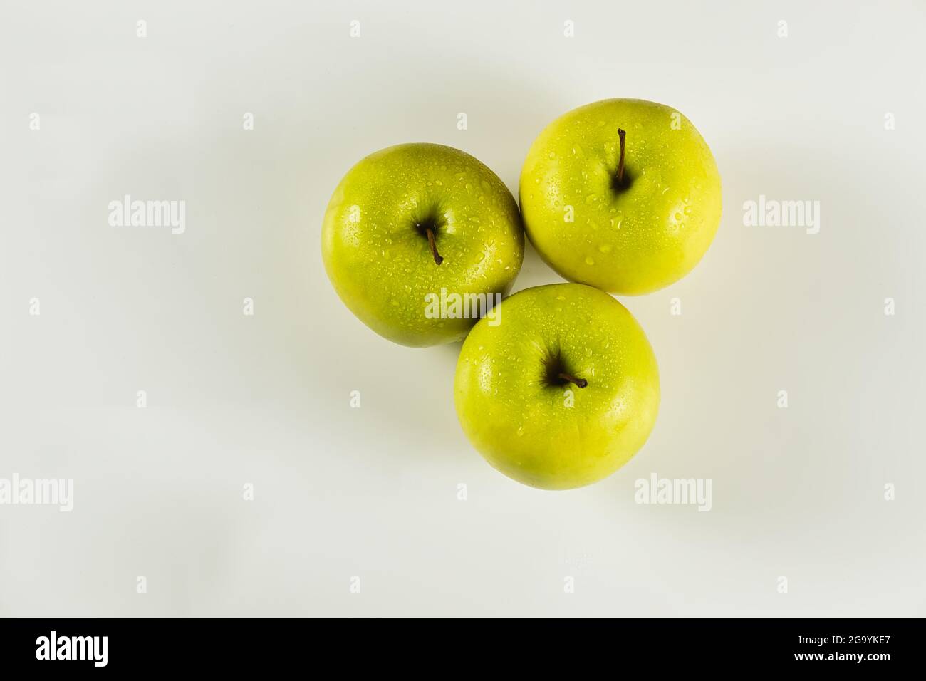 foreground of three green apples with drops on white background viewed from above Stock Photo