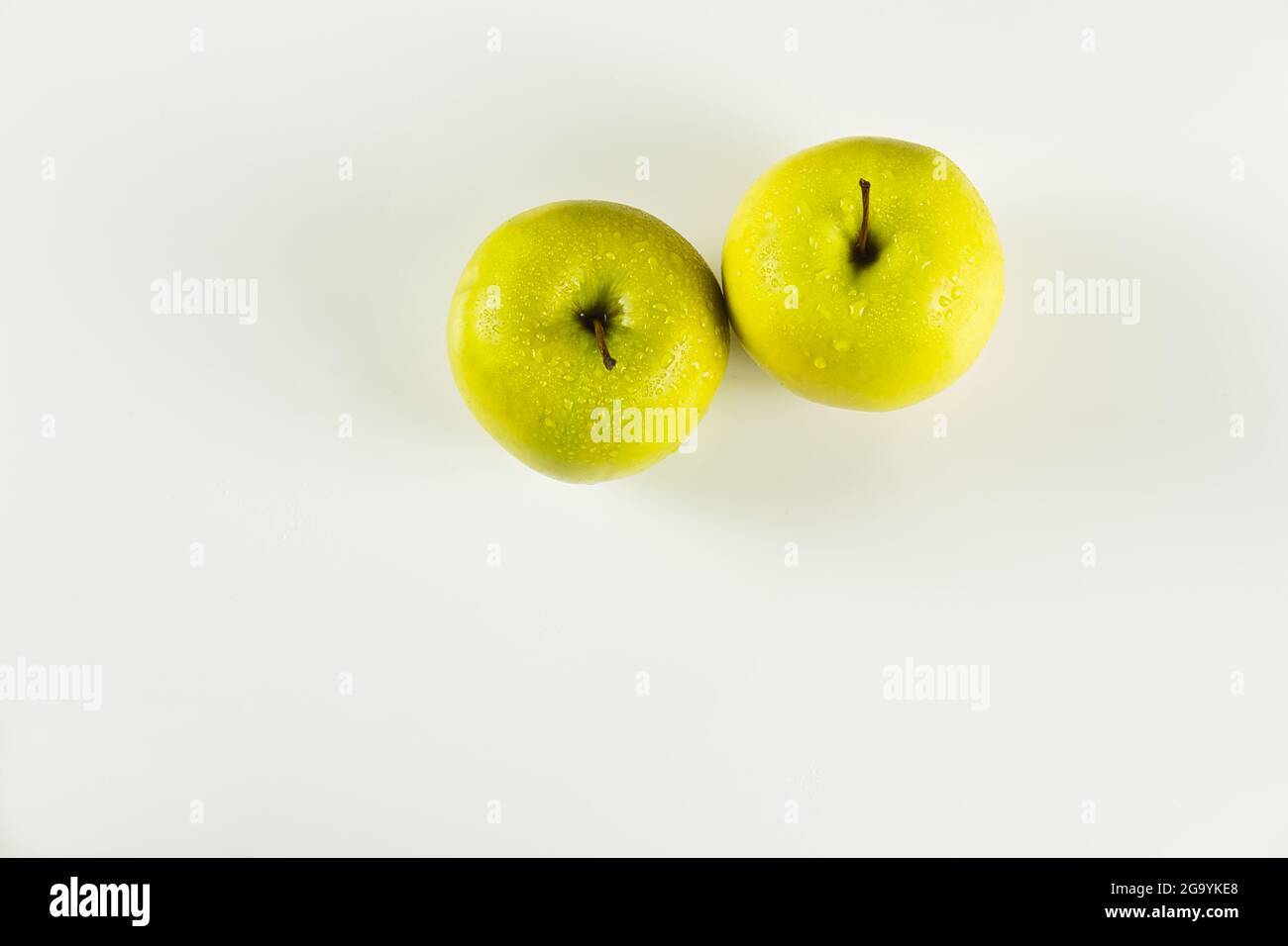 foreground of two green apples with drops on white background viewed from above Stock Photo